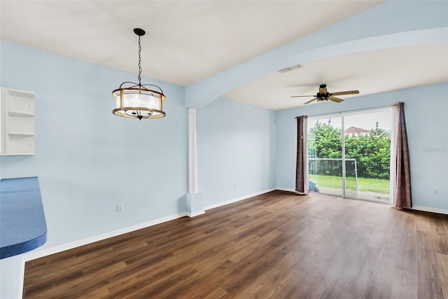 spare room featuring baseboards, visible vents, dark wood-style flooring, and ceiling fan with notable chandelier