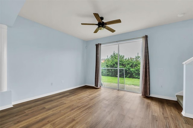 spare room with a ceiling fan, baseboards, wood finished floors, and ornate columns