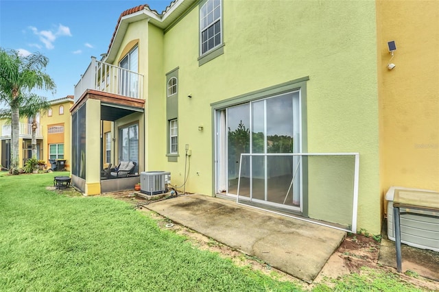 rear view of property with stucco siding, a lawn, central AC unit, a patio area, and a balcony