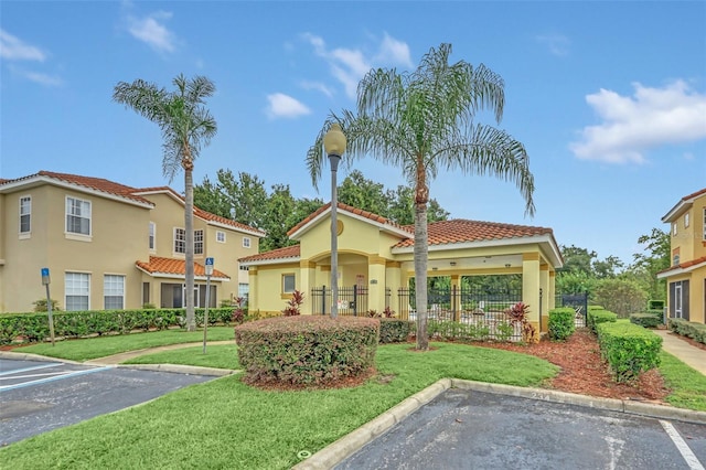 mediterranean / spanish home featuring uncovered parking, a front lawn, fence, and stucco siding