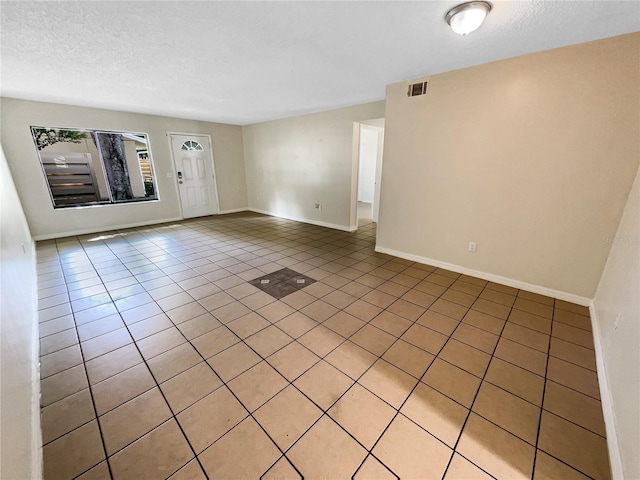 unfurnished living room featuring a textured ceiling and light tile patterned flooring