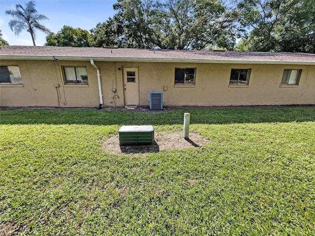 back of house with a lawn and stucco siding