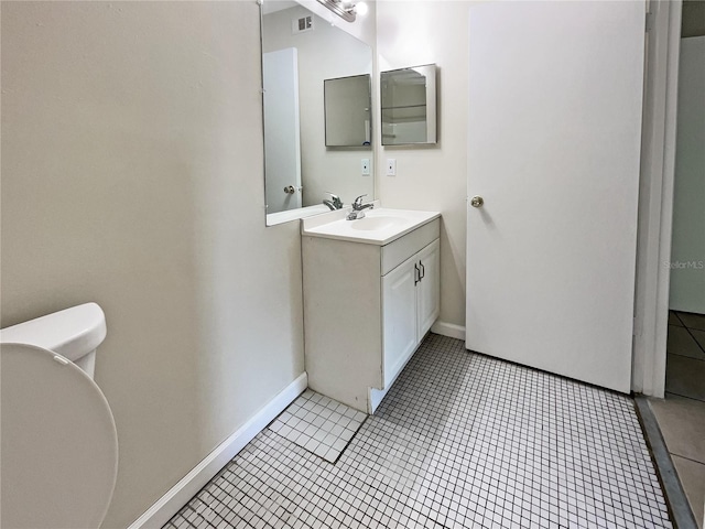 bathroom featuring toilet, vanity, visible vents, baseboards, and tile patterned floors