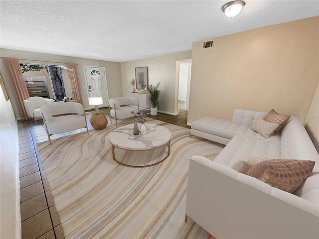 living area with a textured ceiling, visible vents, and baseboards