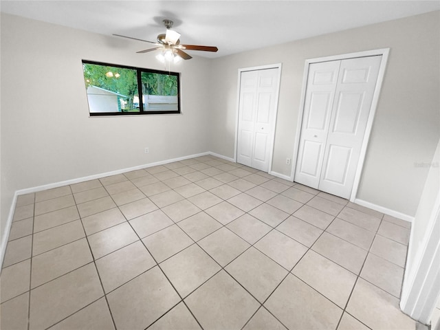 unfurnished bedroom featuring two closets, a ceiling fan, and baseboards