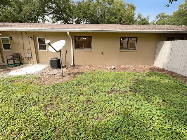 back of property with roof with shingles, fence, a lawn, and stucco siding