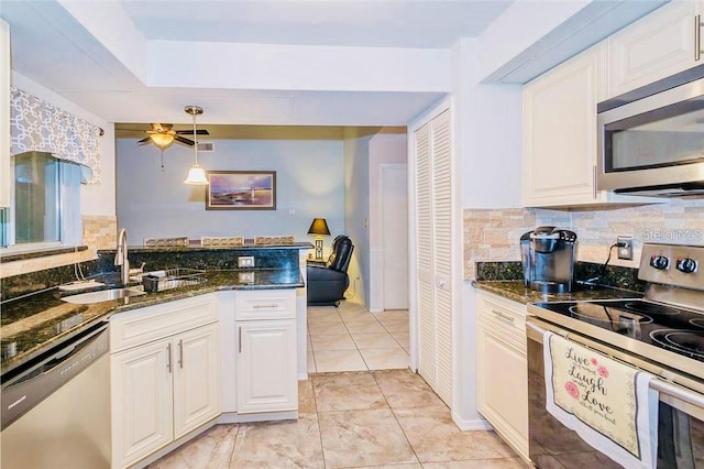 kitchen with backsplash, appliances with stainless steel finishes, sink, white cabinetry, and dark stone countertops