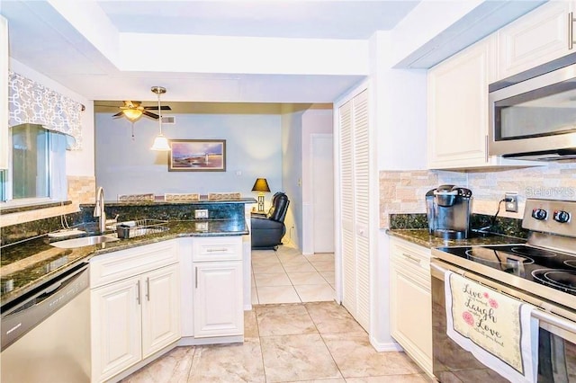 kitchen with appliances with stainless steel finishes, white cabinetry, sink, and dark stone counters