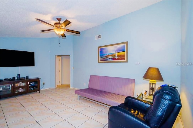 living room featuring lofted ceiling, ceiling fan, light tile patterned floors, and a textured ceiling