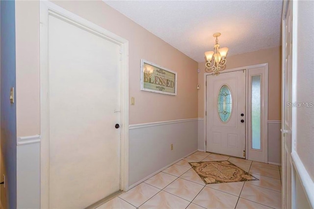 entrance foyer featuring light tile patterned floors, a notable chandelier, and a textured ceiling