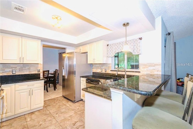 kitchen with decorative light fixtures, appliances with stainless steel finishes, a kitchen bar, kitchen peninsula, and dark stone counters