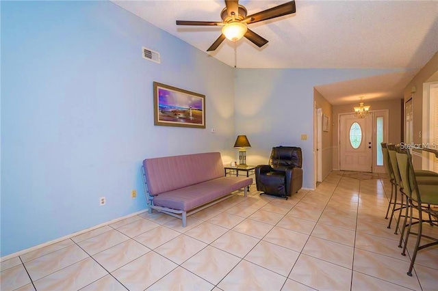 living area featuring ceiling fan with notable chandelier, vaulted ceiling, and light tile patterned flooring