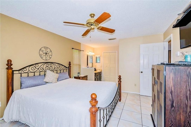 tiled bedroom with a textured ceiling, ensuite bathroom, ceiling fan, and a closet