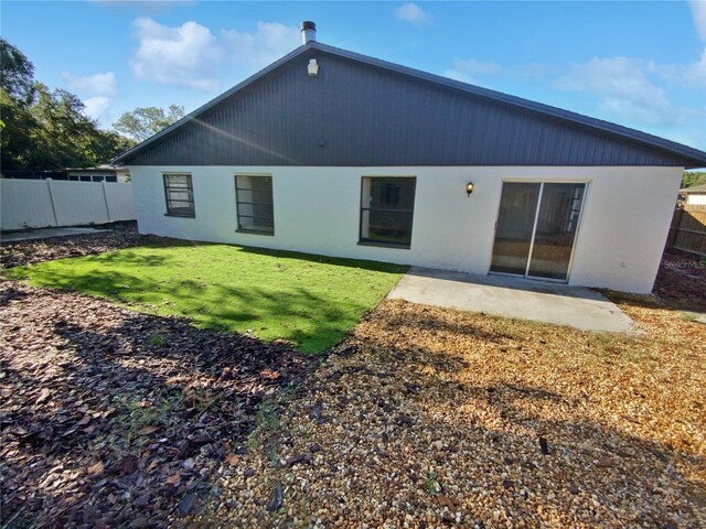 back of property with a lawn and a patio area