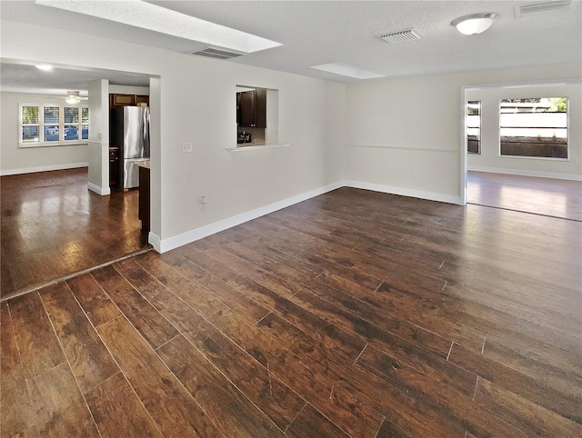 empty room featuring a textured ceiling, dark wood-type flooring, and ceiling fan