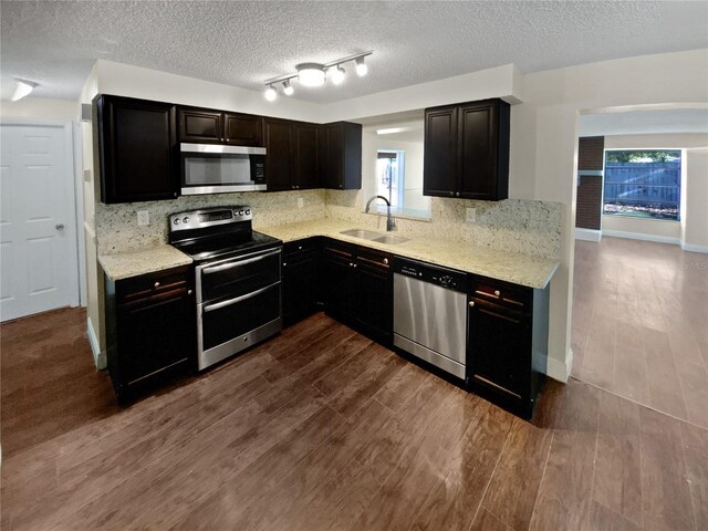 kitchen featuring dark wood-type flooring, stainless steel appliances, sink, and backsplash