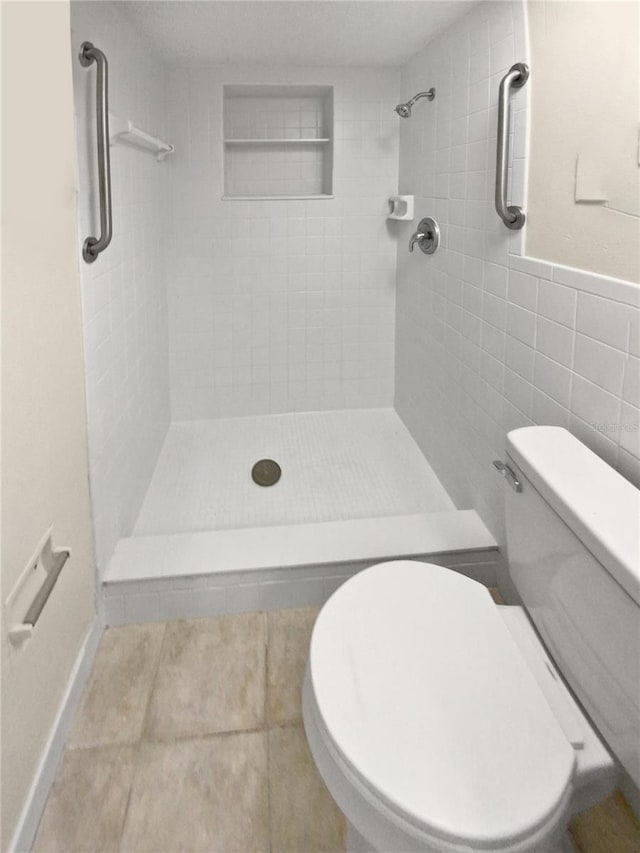 bathroom featuring tile walls, toilet, tiled shower, and tile patterned floors