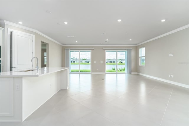 unfurnished living room with crown molding, sink, and light tile patterned floors