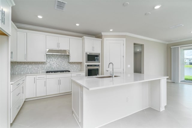 kitchen with white cabinets, stainless steel appliances, sink, light tile patterned flooring, and a kitchen island with sink