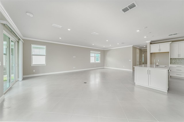 unfurnished living room featuring ornamental molding, light tile patterned floors, and sink