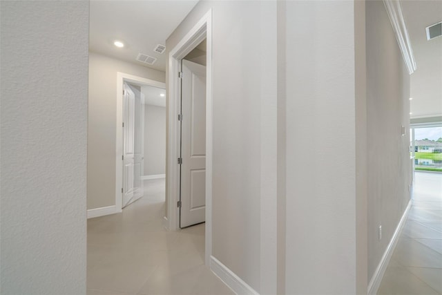 hall featuring ornamental molding and light tile patterned flooring