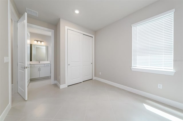 unfurnished bedroom featuring sink, a closet, connected bathroom, and light tile patterned flooring