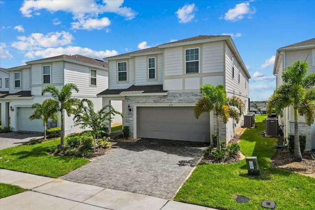 view of front of house with a garage, a front yard, and central AC