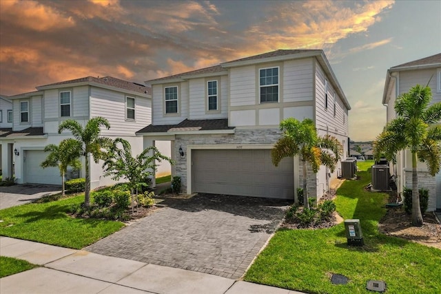 view of front of property featuring a garage, cooling unit, and a lawn