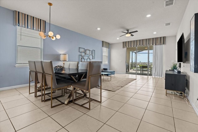 dining space featuring ceiling fan with notable chandelier, a textured ceiling, and light tile patterned floors