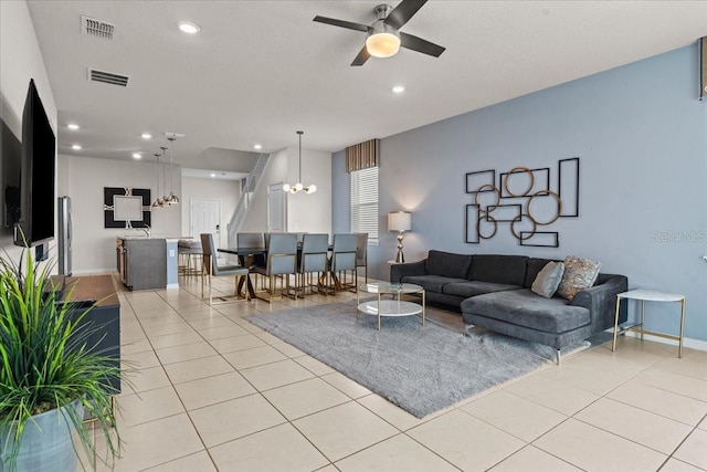 tiled living room featuring ceiling fan with notable chandelier