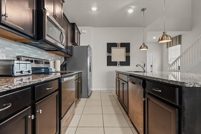 kitchen with sink, hanging light fixtures, light tile patterned floors, stainless steel appliances, and decorative backsplash