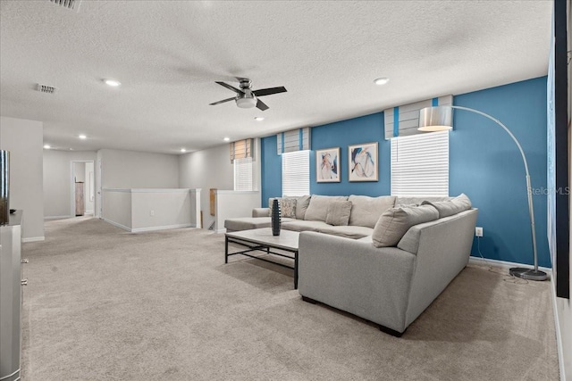 living room featuring light carpet, a textured ceiling, and ceiling fan