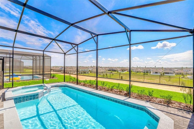 view of pool with a patio, glass enclosure, and an in ground hot tub