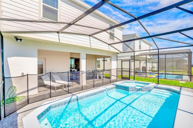 view of pool featuring an in ground hot tub, glass enclosure, and a patio