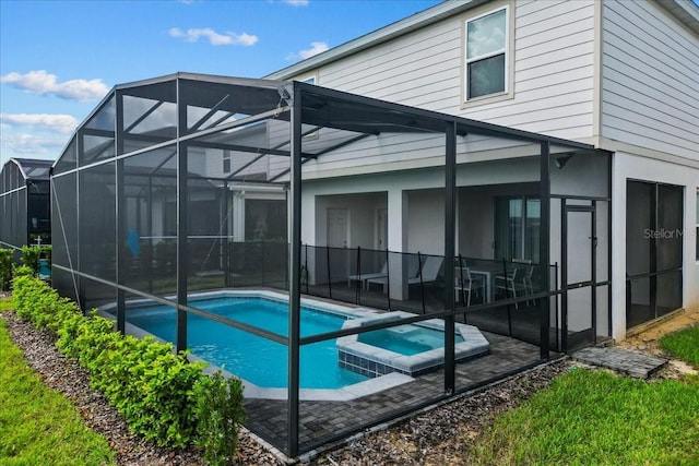 rear view of property with a lanai, a pool with hot tub, and a patio area