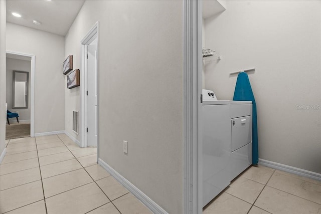 clothes washing area featuring light tile patterned flooring and washer and clothes dryer