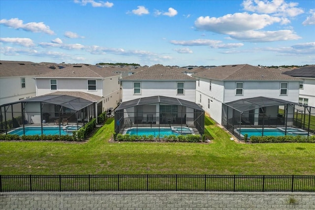 back of property with a yard, a fenced in pool, and glass enclosure