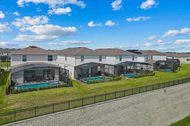 back of property featuring a yard, a fenced in pool, and glass enclosure