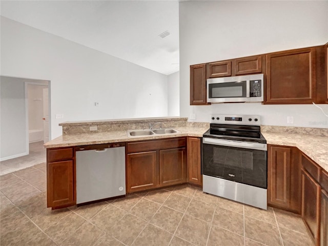 kitchen with kitchen peninsula, sink, light tile patterned floors, and appliances with stainless steel finishes