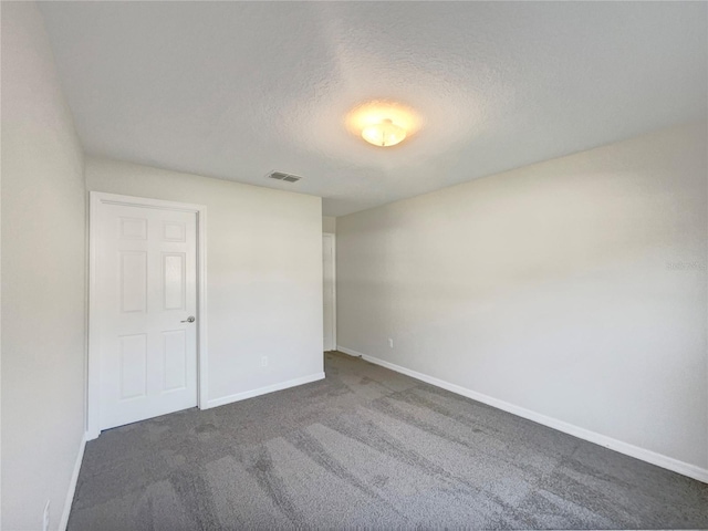 unfurnished room featuring dark carpet and a textured ceiling