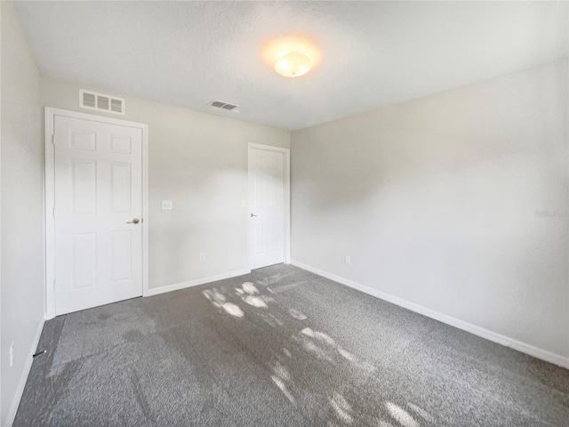 unfurnished room featuring dark carpet, visible vents, and baseboards