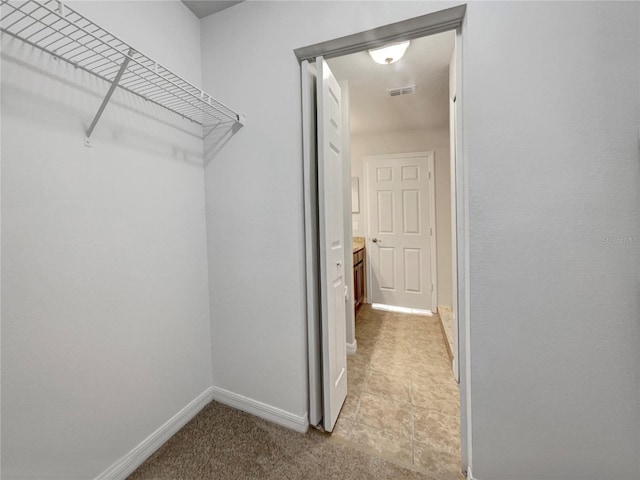 spacious closet with visible vents and light colored carpet