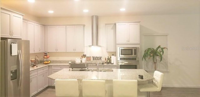 kitchen featuring appliances with stainless steel finishes, light stone counters, an island with sink, and a breakfast bar