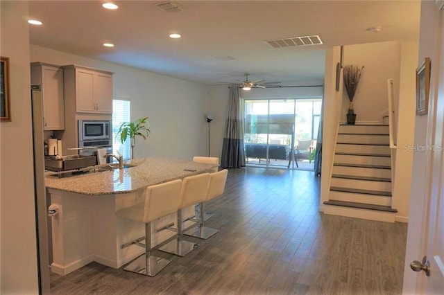 kitchen featuring ceiling fan, a wealth of natural light, a kitchen breakfast bar, and dark hardwood / wood-style floors