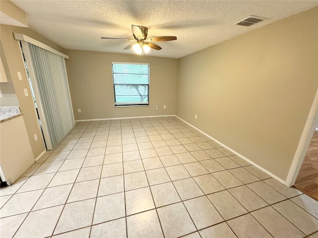 unfurnished room with a textured ceiling, light tile patterned flooring, and ceiling fan