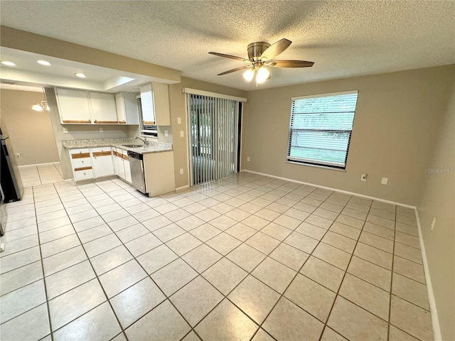 kitchen featuring a sink, white cabinets, light tile patterned floors, baseboards, and dishwasher