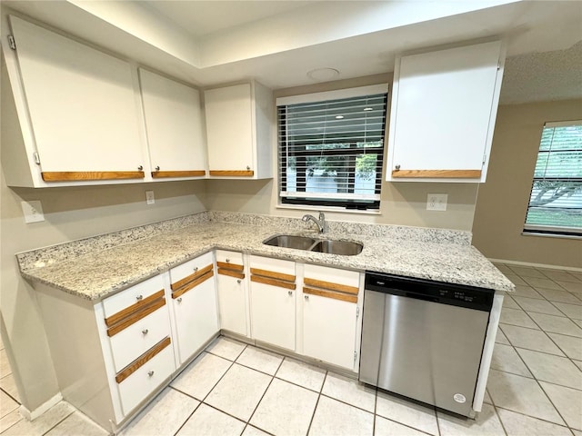 kitchen featuring stainless steel dishwasher, light tile patterned floors, white cabinetry, and a sink