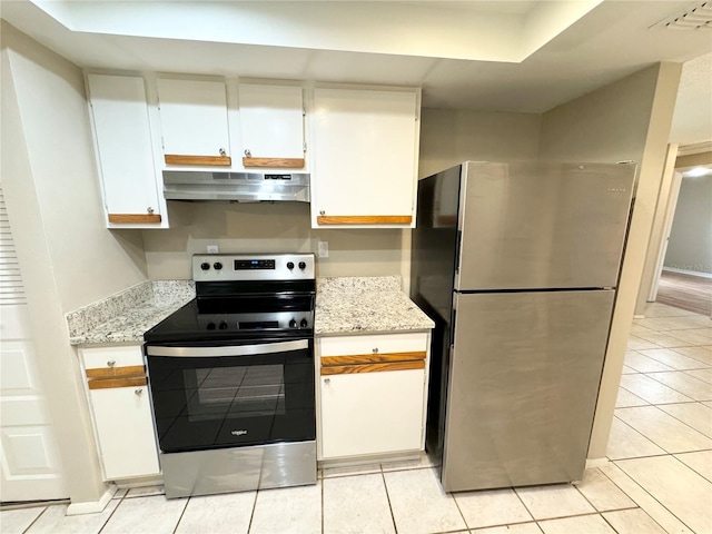 kitchen with under cabinet range hood, light tile patterned floors, light stone counters, white cabinets, and stainless steel appliances