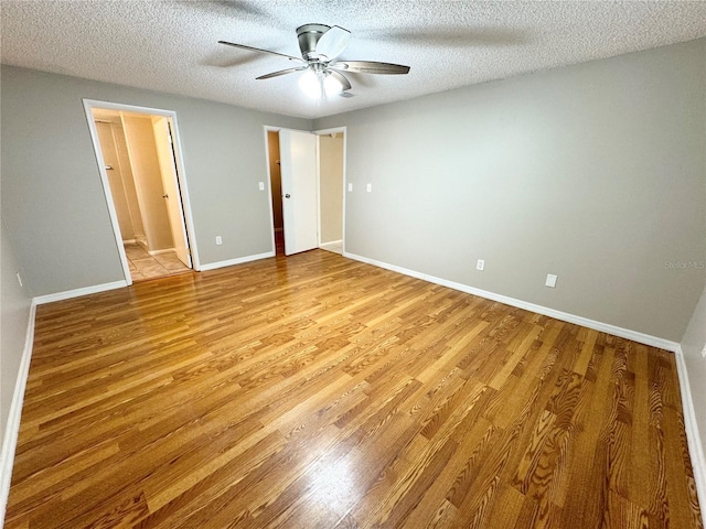 unfurnished bedroom with baseboards, ceiling fan, ensuite bathroom, a textured ceiling, and light wood-type flooring