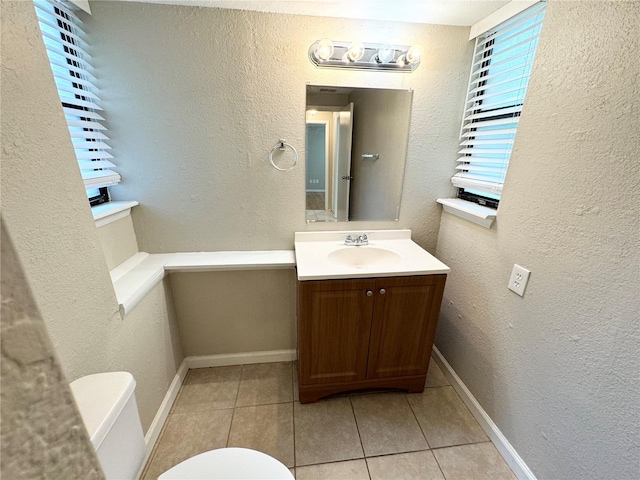 bathroom featuring toilet, vanity, baseboards, and a textured wall